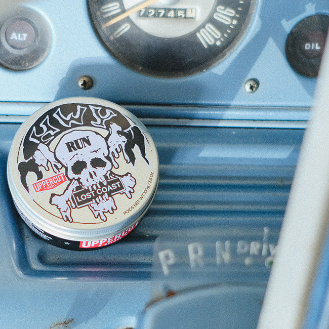 HWY x Uppercut Deluxe Tin sitting on dashboard of car