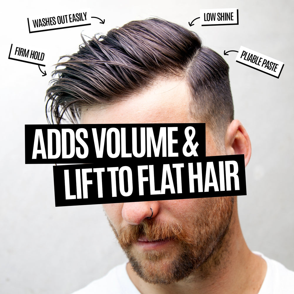 A close-up of a man's styled hair with a side part, showing dark brown to black hair with a low shine finish. Text overlays describe product benefits: 'WASHES OUT EASILY', 'LOW SHINE', 'FIRM HOLD', 'PLIABLE PASTE', and 'ADDS VOLUME & LIFT TO FLAT HAIR'.
