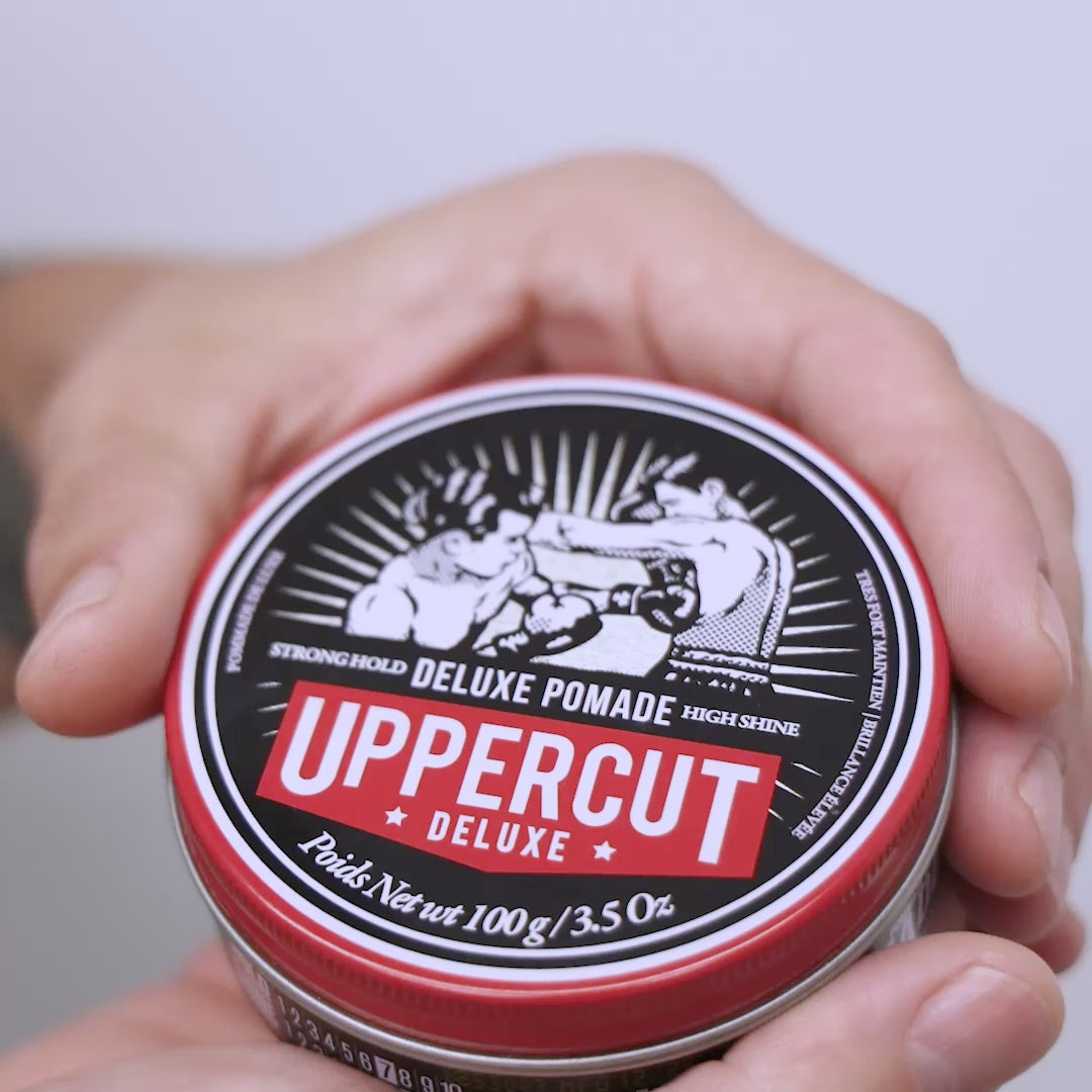Uppercut Deluxe Deluxe Pomade tin being opened, scooped and spread through hands.